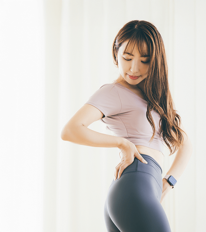 トレーニング服を着た女性がポーズ(腰にて当てて捻りながらのポーズ)を決めている画像
